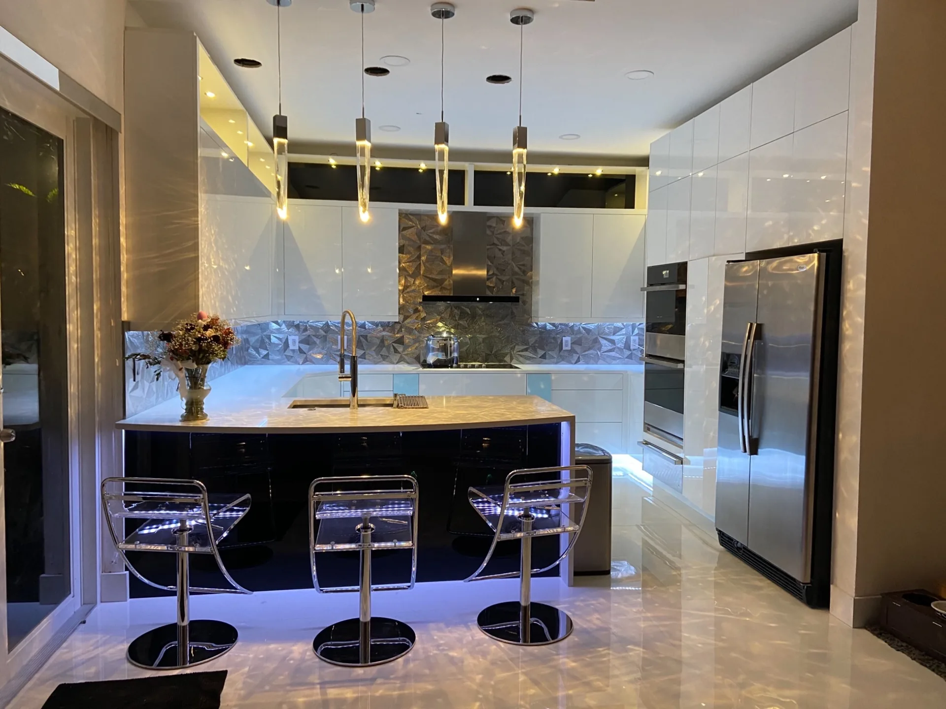 Custom white kitchen with waterfall island and warm cabinet lighting